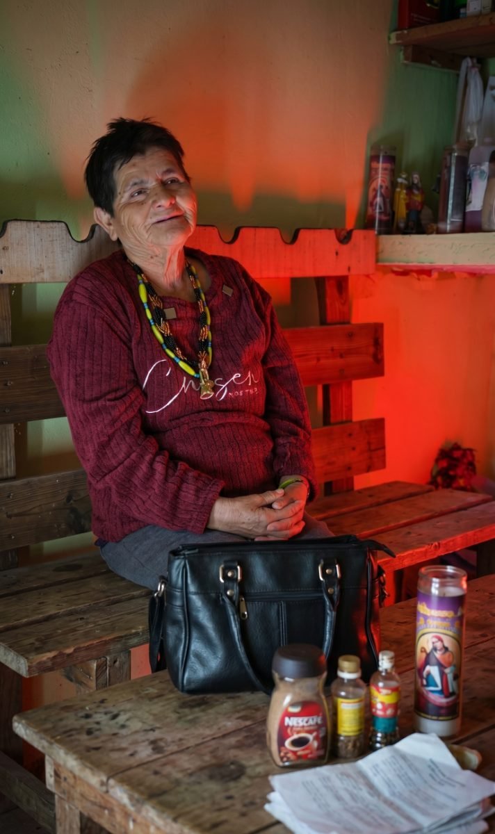 La Bruja Martha Molina Jaramillo sentada con veladoras en su rancho de La Biznaga